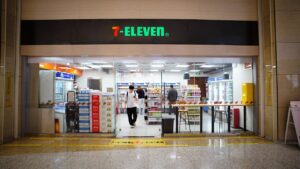 Indoor view of a 7-Eleven store entrance with people shopping and products displayed.