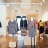Side view of unrecognizable female seller standing and adjusting stylish colorful clothes hanging on rail in boutique in daytime